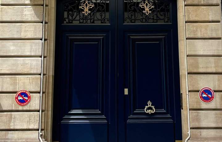 Porte d'entrée en bois massif bleu nuit avec fer forgé doré sur façade haussmannienne en pierre