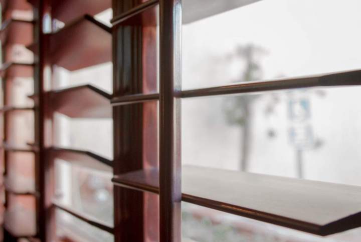Volet à lames inclinées de type persienne sur une fenêtre de façade ancienne
